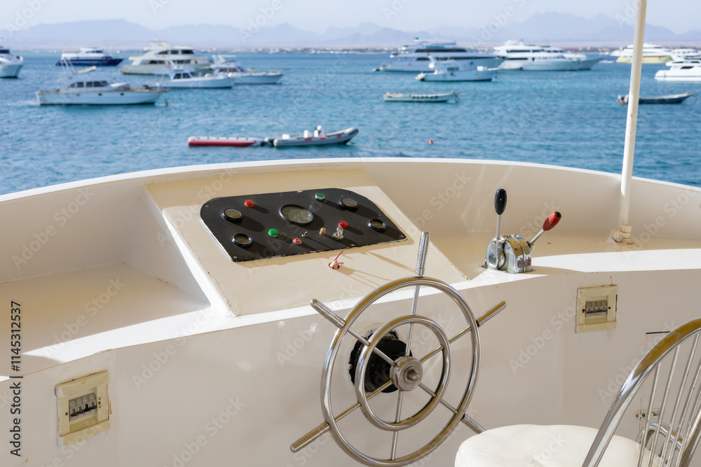 Obraz premium Scenic view of yacht wheel and boats in tranquil blue waters for boating enthusiasts
