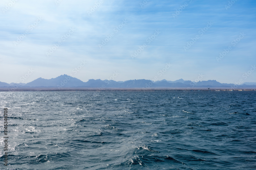 Serene ocean waves and distant mountain landscape under clear blue sky Serene ocean waves and distant mountain landscape under clear blue sky