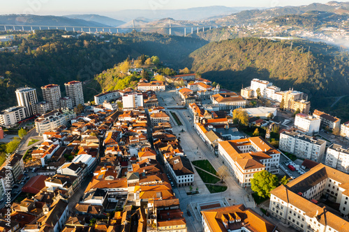 Picturesque drone view of Vila Real cityscape in valley framed by Alvao and Marao mountain ranges in light fog with suspension viaduct crossing Corgo River in background on sunny spring day, Portugal photo