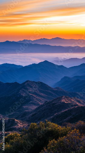 Misty mountains bathed in warm orange and yellow hues at sunset, symbolizing tranquility and the beauty of nature's chaos, a perfect high-definition phone wallpaper to evoke peace and awe