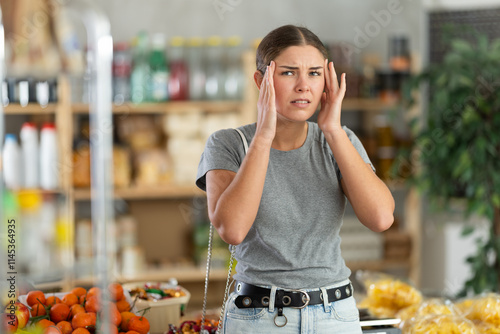 Young woman felt a headache while going to the supermarket for shopping. European woman felt dizzy when visiting the store photo