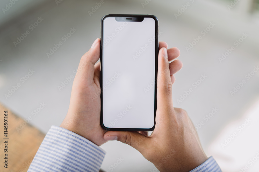 Mockup image of man hand holding using white mobile phone at indoor with copy space, blank screen for text. Mockup image of man hand holding using white mobile phone at indoor with copy space, blank screen for text.