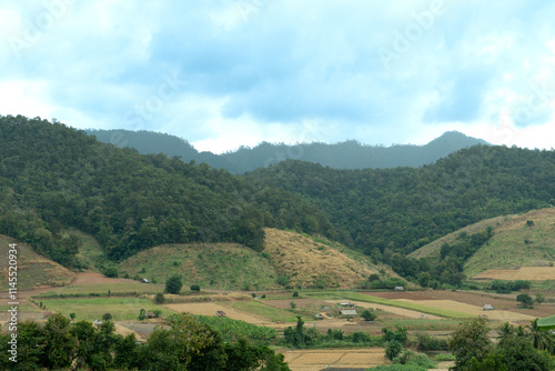 landscape of rolling green hills and valleys under a bright blue sky with scattered white clouds. Landmark hills of Mae La Luang. Mae Hong Son of Thailand.