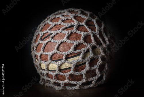 Obraz na płótnie View of Basketball ball inside of Knitting yarn mesh net string bag on black background, Light and Shadow, use it as your Wallpaper, Poster and Copy space, Selective focus. w salonie