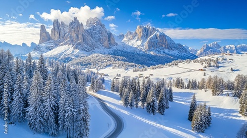 top-down aerial picture of a road, trees, and snow-covered mountains. Dolomites, Italy. 