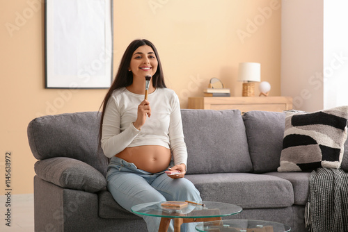 Beautiful pregnant woman putting on makeup at home