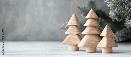 Wooden Christmas tree toy decoration in a minimalist setting with a gray background and snowy pine branches for festive seasonal decor