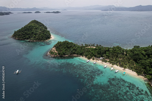 Aerial picture of a remote island next to Port Barton in the Philippines. Holidays in Asia, hopping island activity. Beautiful bay, white beach, coconut trees, coral reef and blue ocean with boats.