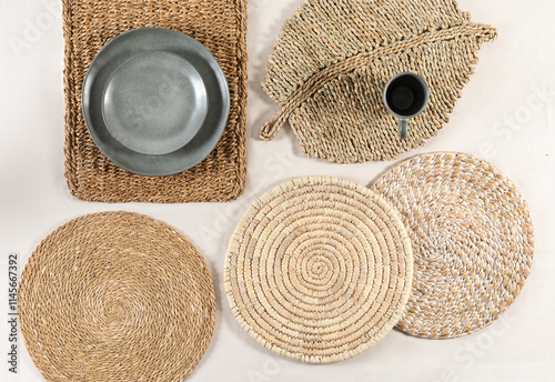 Top-view composition of handcrafted woven placemats in natural fibers, textured ceramic dinnerware in soft gray tones, and minimalist décor accents gracefully evoking warmth and organic elegance.