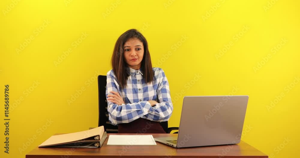 Serious young asian businesswoman sitting at desk working on laptop feeling angry and unhappy isolated over yellow background. Serious young asian businesswoman sitting at desk working on laptop feeling angry and unhappy isolated over yellow background.