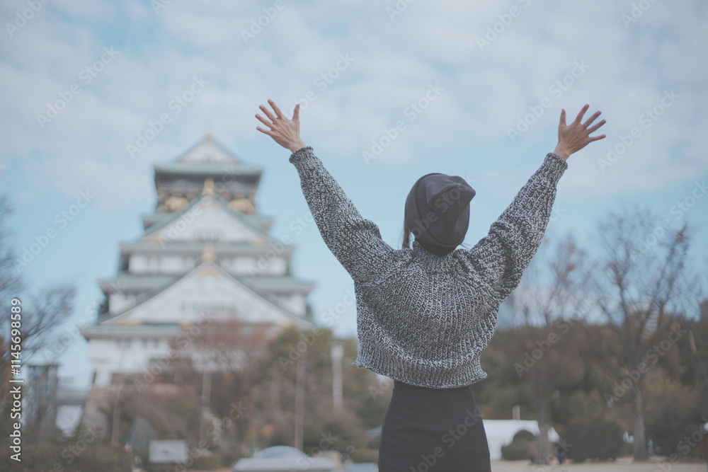 Fototapeta premium 大阪城と喜ぶ女性旅行者の後ろ姿