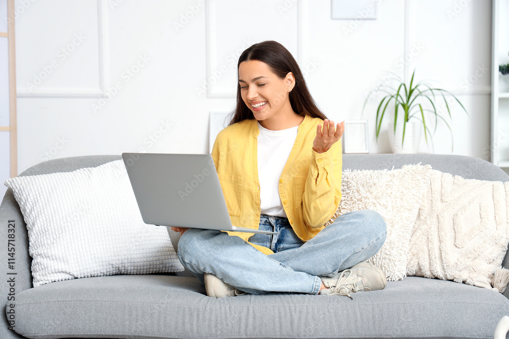 Beautiful young woman with laptop video chatting on sofa at home Beautiful young woman with laptop video chatting on sofa at home