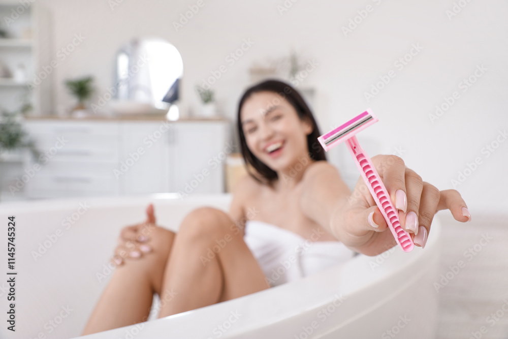 Obraz premium Beautiful young happy woman with razor sitting in bathtub at home