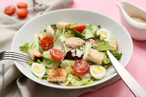 Bowl with tasty Caesar salad on pink background