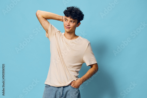 Young man posing against a light blue background, casual attire with a relaxed expression, showcasing modern fashion and confidence in a simple yet stylish manner photo