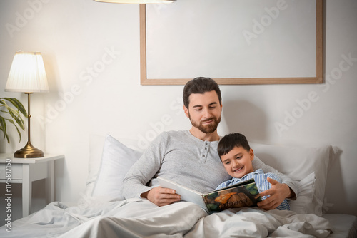 Father reading bedtime story to his little son in bedroom