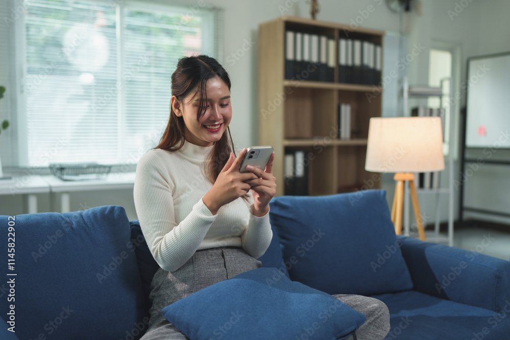 Attractive Asian woman Smiling while talking on the cell phone with co-workers, shopping online. Happy chatting while relaxing on the sofa in the living room at home. Holiday concept. Attractive Asian woman Smiling while talking on the cell phone with co-workers, shopping online. Happy chatting while relaxing on the sofa in the living room at home. Holiday concept.
