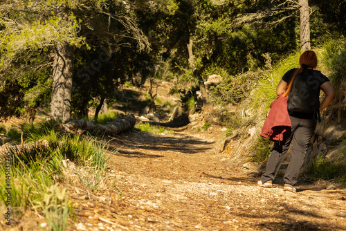 Woman hiking up a slope of a rocky path in nature on a sunny day with copy space