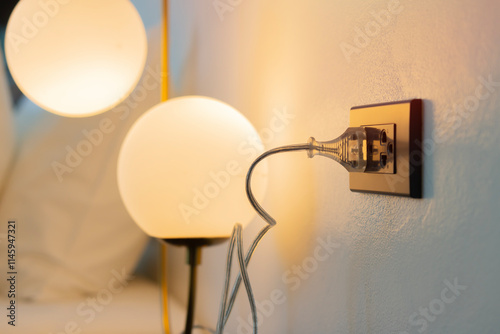 Illuminated electric lamp and electric socket in bedroom. Bright light illuminates hotel room