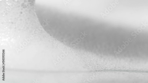 White cosmetic foam with a makeup brush, close-up.