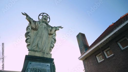 Christus Koning statue near historic church spires and lush green hedges in a serene Dutch setting. Location: Geldrop, Noord-Brabant, Netherlands, Nederland photo