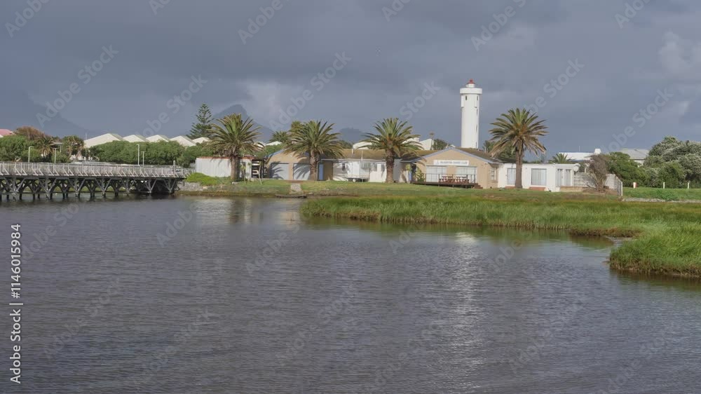 Woodbridge Island lighthouse with palm trees and water reflecting cloudy skies in Cape Town Woodbridge Island lighthouse with palm trees and water reflecting cloudy skies in Cape Town