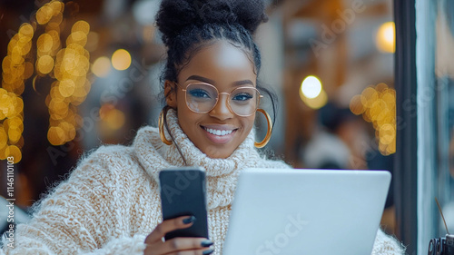Happy Black Woman using Laptop and Phone in Cafe
