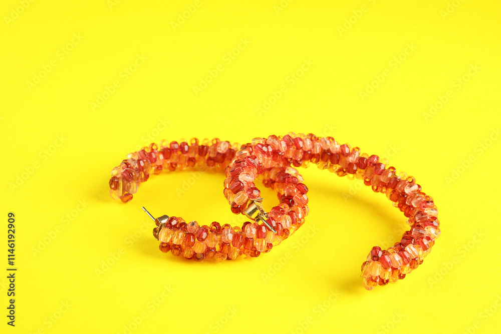 Beautiful bijouterie. Stylish earrings on yellow background, closeup Beautiful bijouterie. Stylish earrings on yellow background, closeup