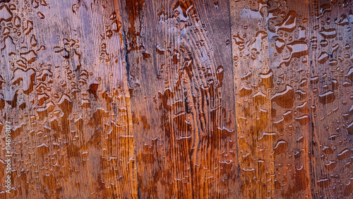 Water droplets on wooden surface. A detailed view of water droplets scattered across a wooden surface.