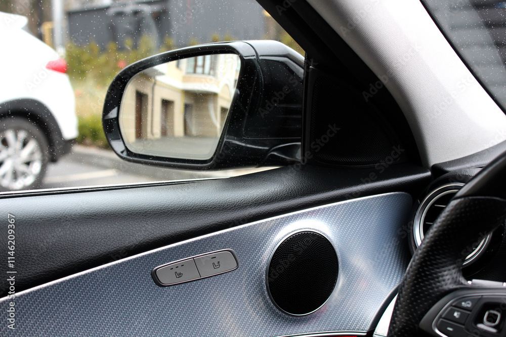 Car interior with view of air conditioner vent and side view mirror and AC vent for air flow in passenger side. Sound speaker in a modern car door panel. Close up car speaker on car door panel