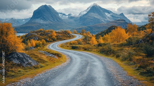 Winding road through autumnal landscape with mountains.