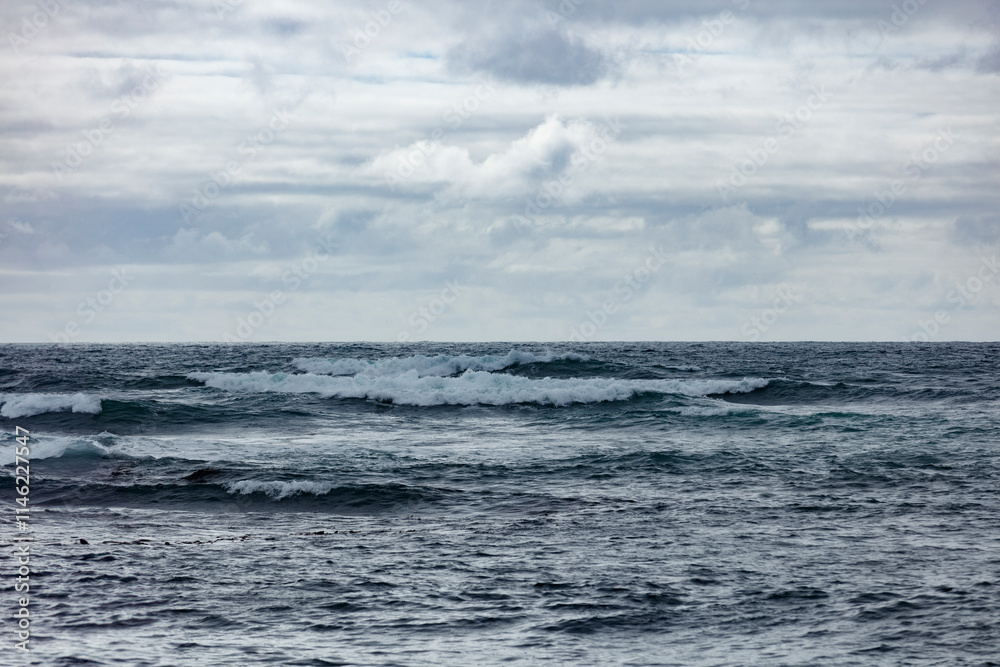 Ocean waves under a cloudy sky. Rough water, light gray clouds. Calm, overcast day. Ocean waves under a cloudy sky. Rough water, light gray clouds. Calm, overcast day.