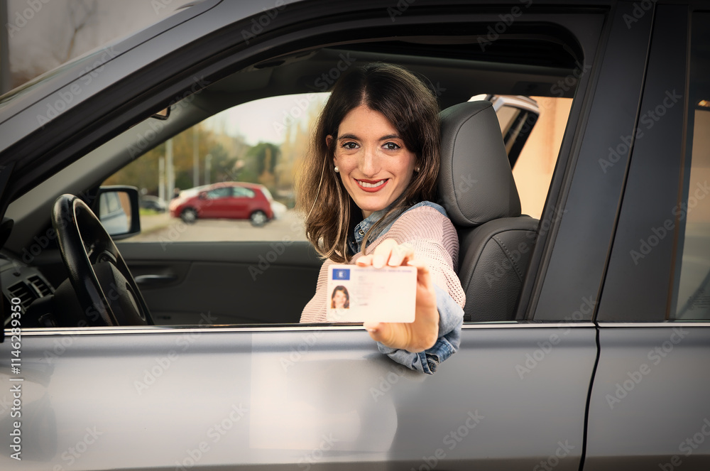 Young woman showing driving license from inside car