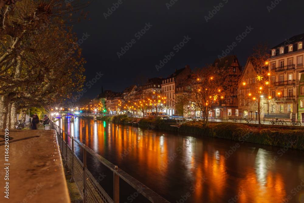 Obraz premium Illuminated riverside promenade in Strasbourg at night.