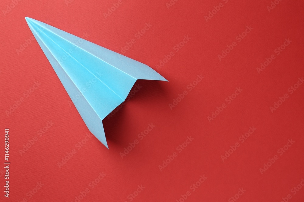One handmade light blue paper plane on red background, top view. Space for text One handmade light blue paper plane on red background, top view. Space for text