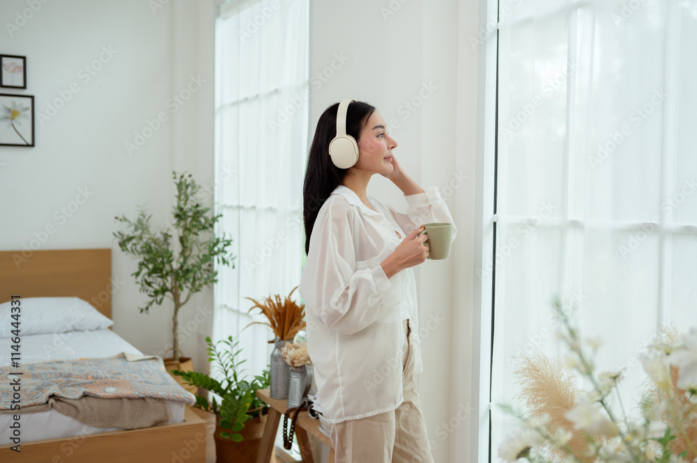 Young Asian woman wearing headphones enjoying music in bedroom at home Young Asian woman wearing headphones enjoying music in bedroom at home