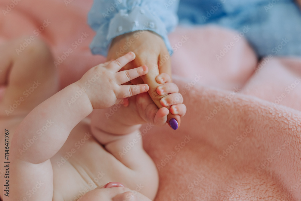 A baby is being held by a woman's hand. The baby is laying on a pink blanket A baby is being held by a woman's hand. The baby is laying on a pink blanket