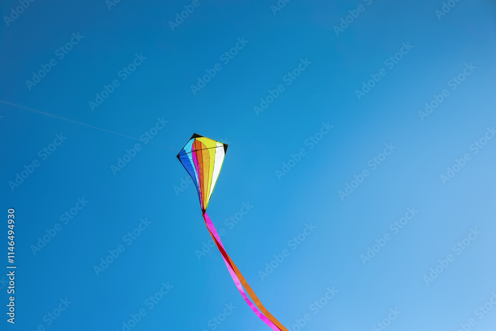One colorful kite flying in sky on sunny day One colorful kite flying in sky on sunny day