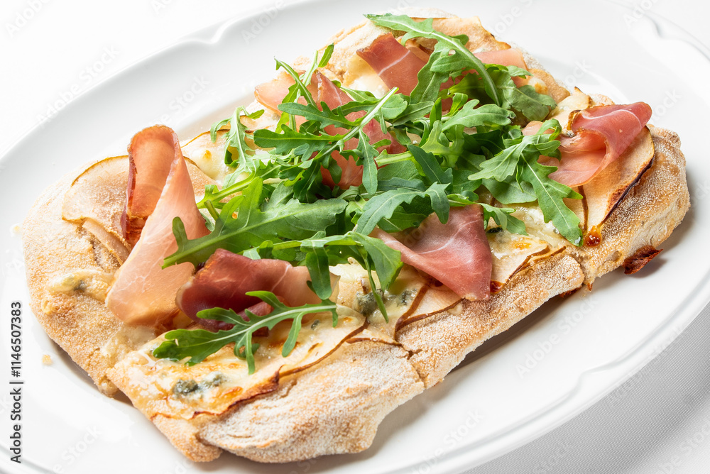 A delicious flatbread topped with prosciutto and fresh arugula, beautifully presented on a white plate. Perfect for gourmet food promotions and culinary articles. A delicious flatbread topped with prosciutto and fresh arugula, beautifully presented on a white plate. Perfect for gourmet food promotions and culinary articles.