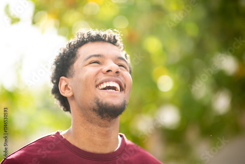 Smiling man looking up in outdoor setting with greenery