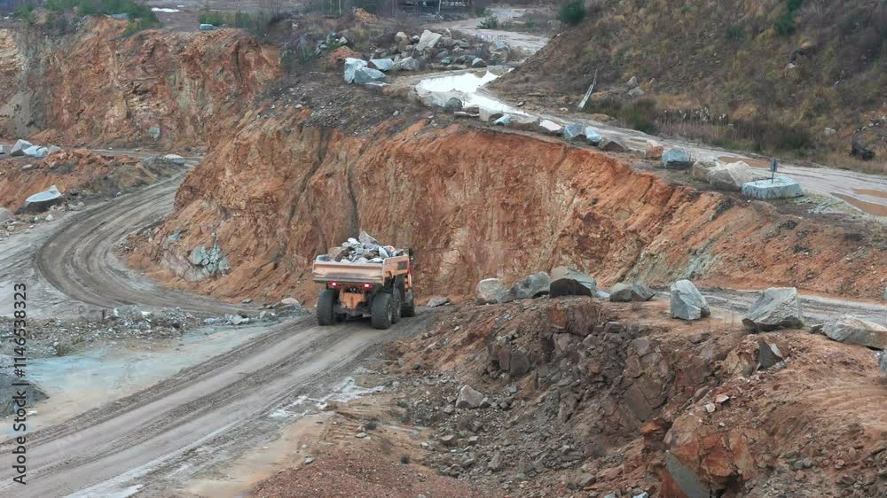 Massive haul trucks carry rocks to the crusher as an excavator loads them in a busy quarry. Industrial machinery works efficiently in full swing. Massive haul trucks carry rocks to the crusher as an excavator loads them in a busy quarry. Industrial machinery works efficiently in full swing.