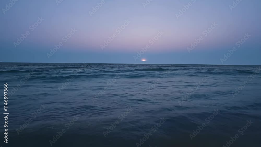 Calm ocean waves ripple under a soft twilight sky at the shoreline during sunset Calm ocean waves ripple under a soft twilight sky at the shoreline during sunset