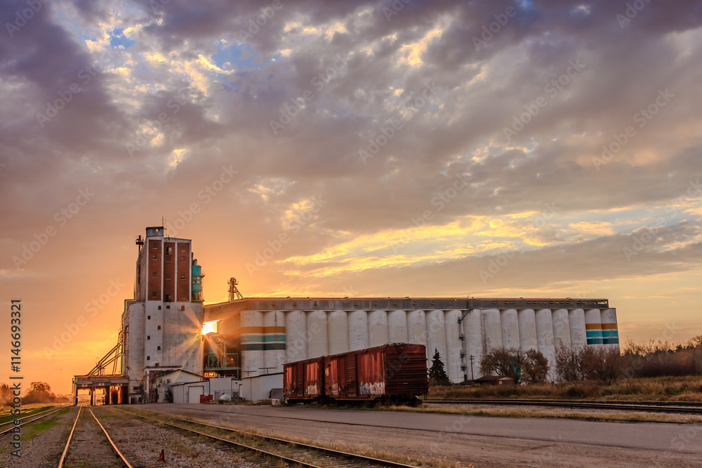 A train is parked in front of a large grain silo A train is parked in front of a large grain silo