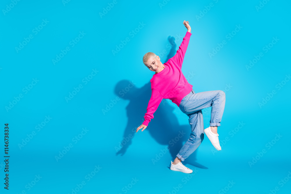 A young woman in a casual, stylish pink pullover poses dynamically against a vibrant blue background A young woman in a casual, stylish pink pullover poses dynamically against a vibrant blue background