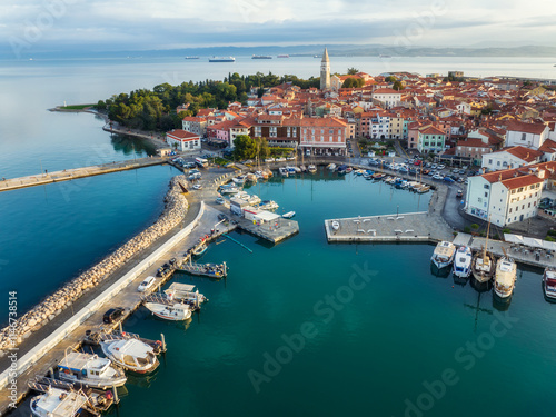 Aerial panoramic view of picturesque Izola town with the old town and buildings with red roofs, the main promenade, the marina with boats on Adriatic sea coast, Slovenia.