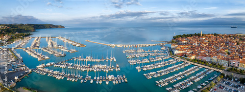 Aerial panoramic view of picturesque Izola town with the old town and buildings with red roofs, the main promenade, the marina with boats on Adriatic sea coast, Slovenia.