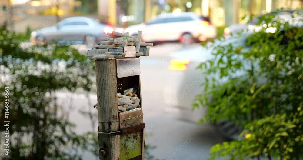 Cigarette butts in large numbers lie in and on overflowing outdoor ashtray. While more people are leaning towards quitting smoking, many still continue this habit. Cigarette butts in large numbers lie in and on overflowing outdoor ashtray. While more people are leaning towards quitting smoking, many still continue this habit.