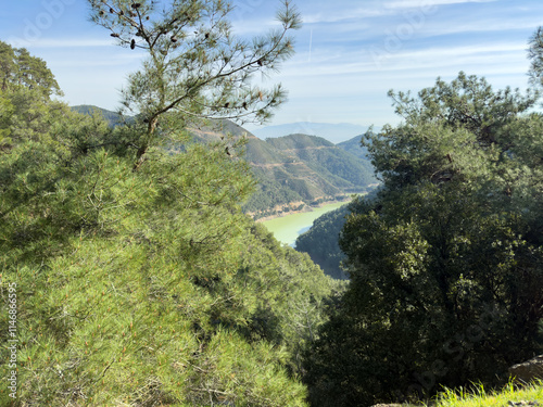 A breathtaking view of a green river winding between two hills, surrounded by lush Mediterranean forest. The serene landscape captures the beauty of nature, perfect for hiking or outdoor inspiration. photo