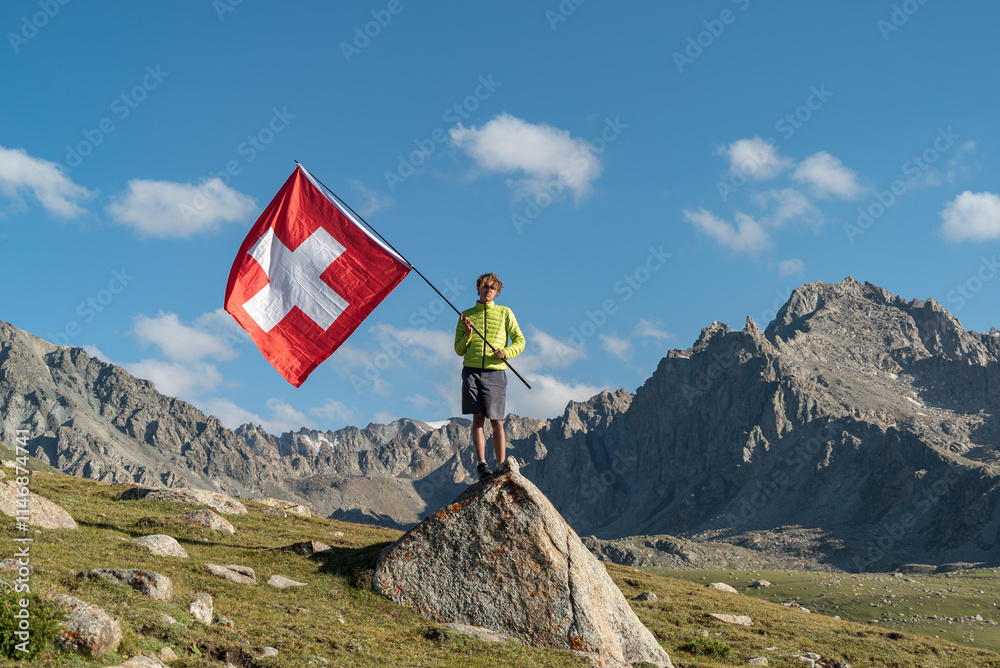 Obraz premium Hiker Man waving an Switzerland flag. The tourist reached the summit.