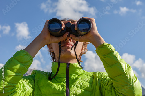 Hiker looking through binoculars on the mountain
Young man using binoculars. Man looking through binoculars at the coast.